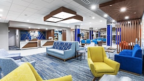 A modern hotel lobby with a reception desk, seating area, and a dining space. - Holiday Inn Express & Suites Houston SW - Rosenberg by IHG (Richmond)