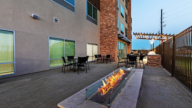An outdoor patio with a fire feature, seating, and a stone pillar. - Holiday Inn Express & Suites Houston SW - Rosenberg by IHG (Richmond)