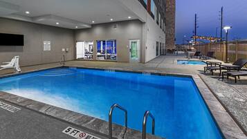 Una piscina al aire libre, sillones reclinables de piscina