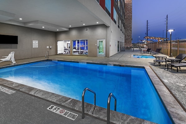 A swimming pool with a lifeguard on duty sign, a no diving sign, and a 5 ft depth marker.