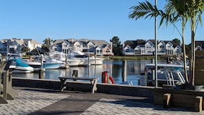 Een jachthaven met aangemeerde boten, een houten bankje en huizen op de achtergrond.