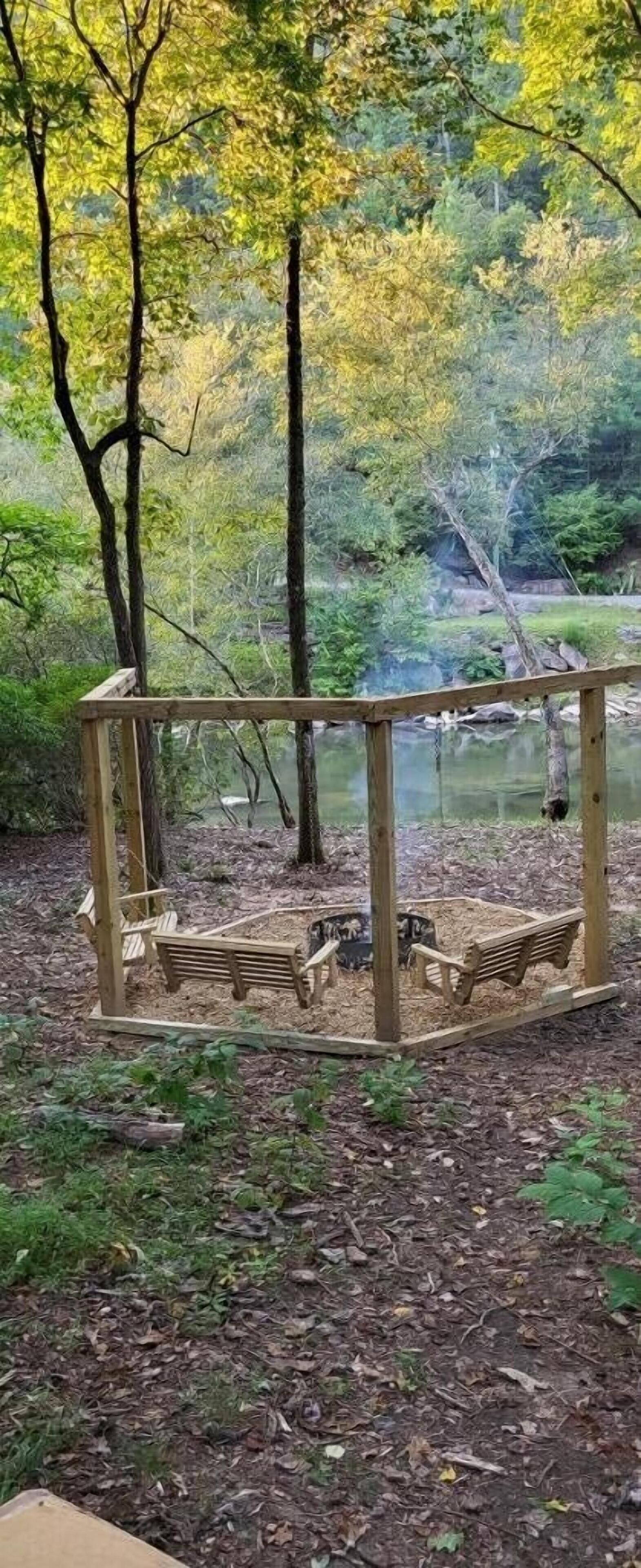 A wooden deck with benches and a view of a pond surrounded by trees.