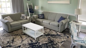 Een woonkamer met twee grijze banken, een witte salontafel en een vloerkleed met dessin.