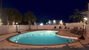 Une piscine avec des chaises longues et une clôture blanche.