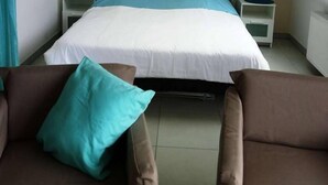 Quarto com cama, duas mesas de cabeceira com luminárias, uma janela e duas poltronas.