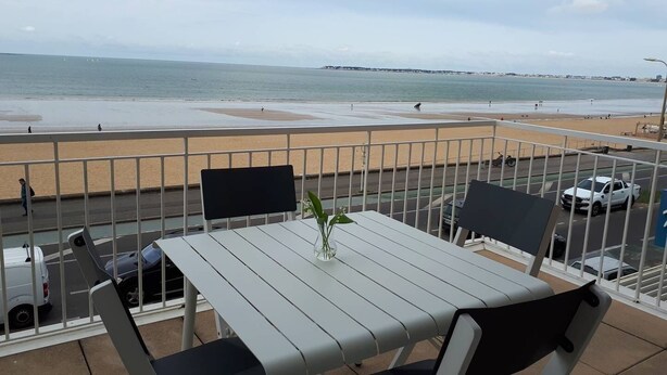 Un balcone con tavolo e sedie che si affaccia su una spiaggia.
