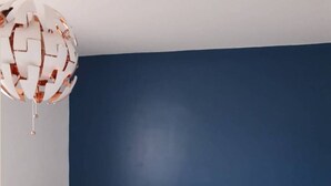 Una camera da letto con una coperta a motivi, una parete blu e un lampadario.