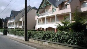 A row of two-story buildings with balconies, a flat roof, and a hedge in front. - Location de Vacances - Pornichet-2 Pièces-005-60282 (PORNICHET)