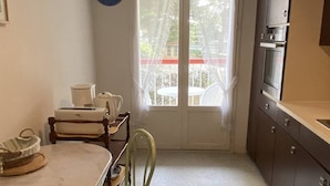 Eine kompakte Küche mit Essbereich, ein Fenster mit Blick auf einen Balkon und eine Uhr an der Wand.
