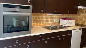Eine Küche mit dunkelbraunen Schränken, einem Edelstahlbackofen, einer Mikrowelle und einem Geschirrspüler.