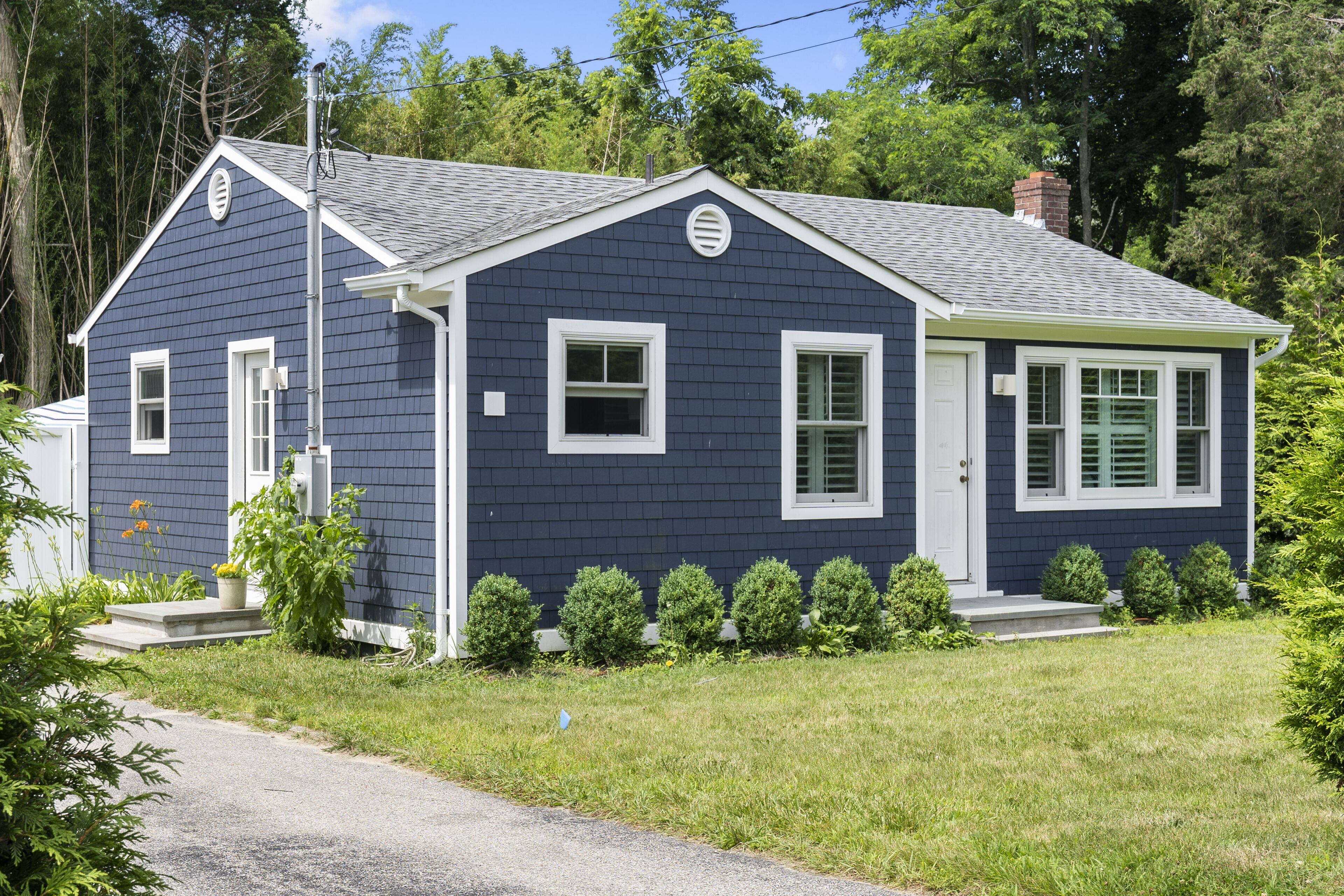 A two-story house with a dark blue exterior, white trim, and a small front porch.