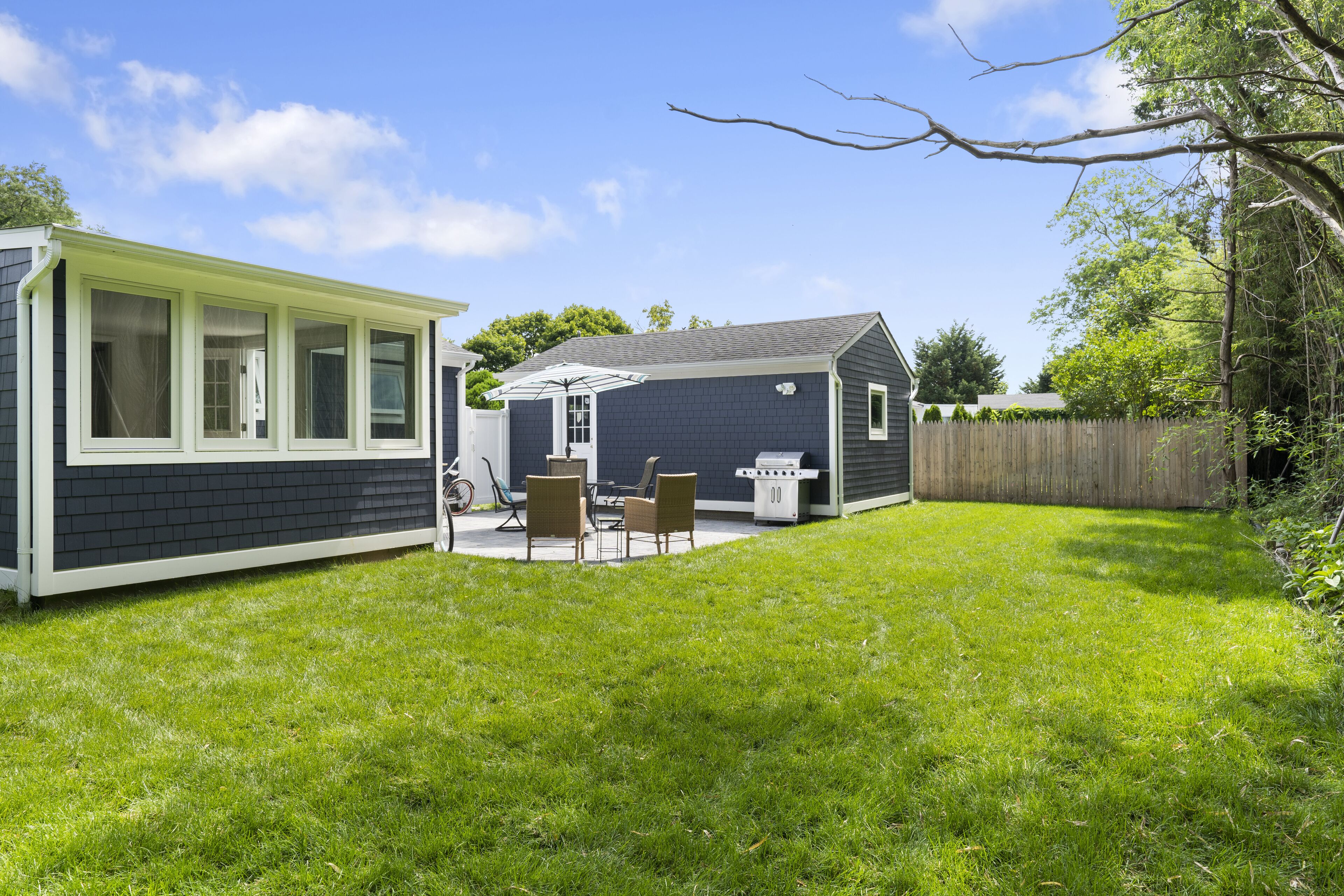 A backyard with a patio, a grill, and a small shed.