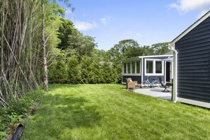 A backyard with a lawn, a covered patio, and a bicycle. - Beautiful remodeled 2 bedroom home — 5 min from the beach! 20 percent for week  (east quogue)