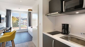 Una cocina moderna con microondas, cafetera y un ventanal grande.