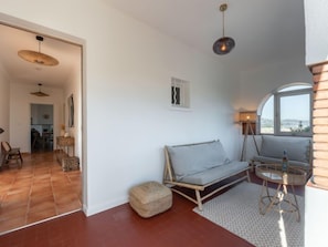 A modern living room with a sofa, a round table, and a view through a window.