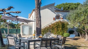 An outdoor patio with a stone floor, a table set for dining, and a large umbrella providing shade. - Lou Niou by Interhome (Saint-Tropez)