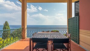 Ein Balkon mit Tisch und Stühlen und Blick auf die Küste.