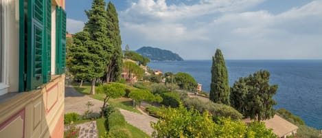 A coastal property with a garden, a view of the sea, and a building with green shutters.