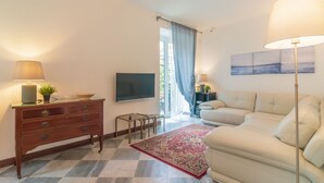 A living room with a sofa, TV, wooden cabinet, and a patterned rug.