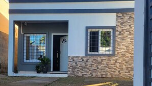 Une maison moderne à deux étages, dotée d’un toit plat, d’une façade en pierre et d’une porte de garage.
