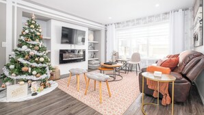 En moderne stue med et juletræ, lædersofa og et fladskærms-tv.