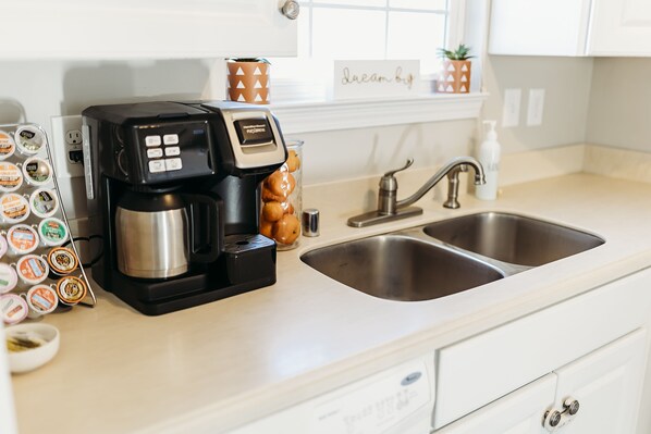 Eine Küche mit Kaffeemaschine, Spüle und Schrank.