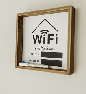 Ein gerahmtes Schild mit einem WLAN-Symbol sowie Feldern für ein Netzwerkpasswort und Passwort.