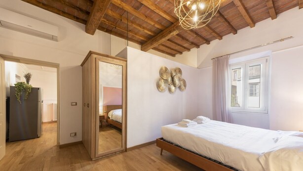 Ein Schlafzimmer mit Holzboden, einem Bett, einem Spiegel und einem Wandbild.