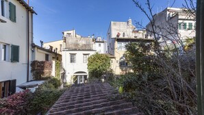 Eine enge Straße mit einer steilen Backstiege, die bergauf führt, umgeben von Gebäuden mit Balkonen und Fensterläden.