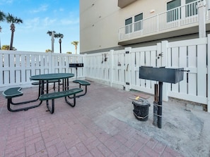 Un patio con tavolo da picnic, barbecue e cassetta delle lettere.