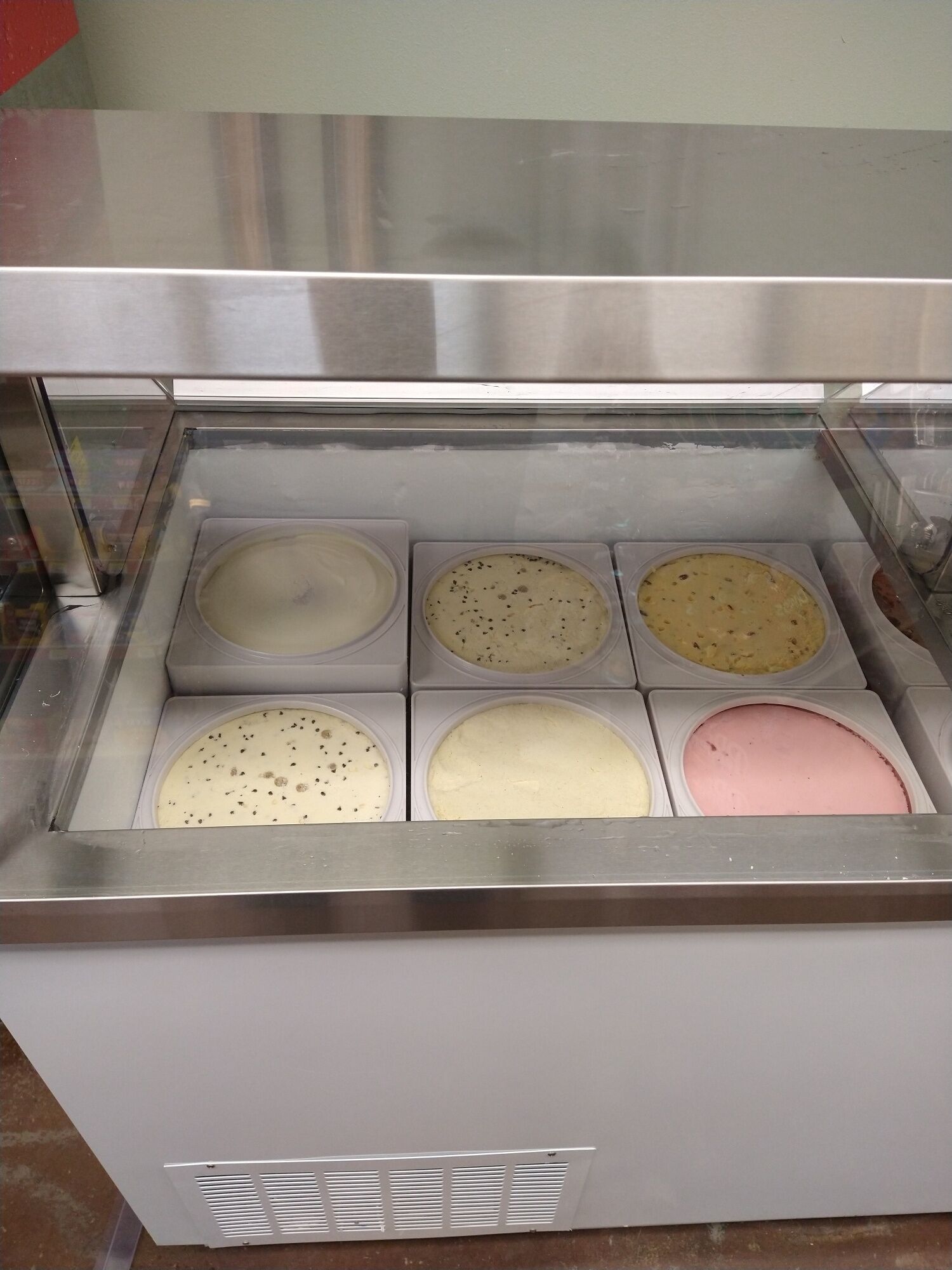 Un présentoir réfrigéré pour aliments, doté de six compartiments contenant différents types de glaces.