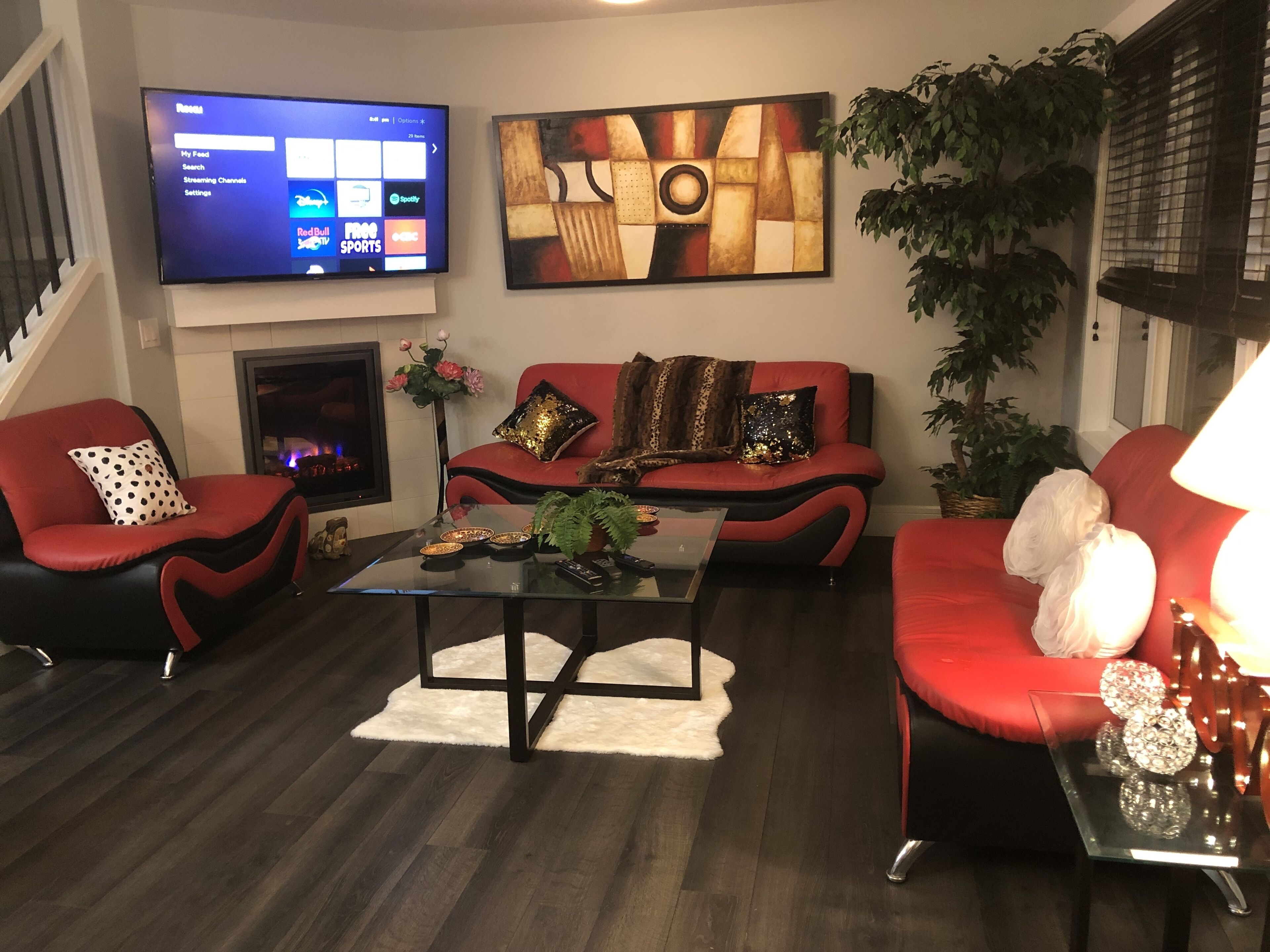 Una sala de estar con televisión de pantalla plana, chimenea y un cuadro abstracto moderno.