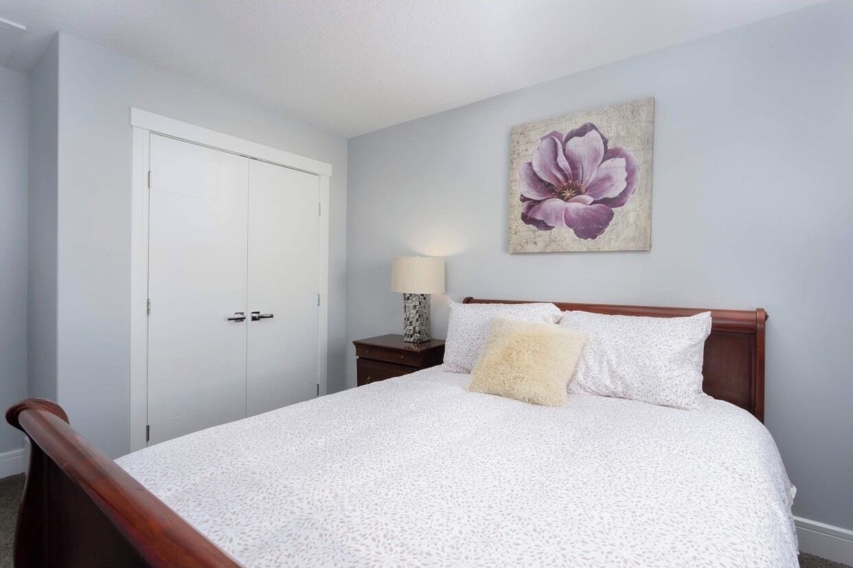 Quarto com cama, mesa de cabeceira, abajur e porta.