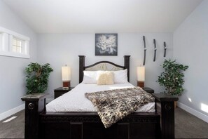 Cozy retreat with a dark bed frame, bedside tables, and a large window.