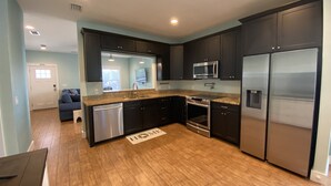 Una cucina moderna con mobili scuri, elettrodomestici in acciaio inossidabile e pavimento in legno.