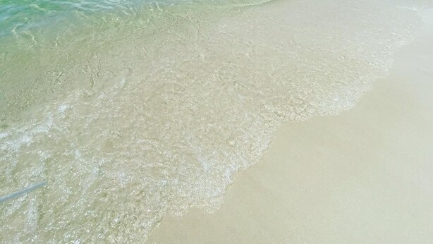 Una spiaggia con acque cristalline turchesi e una battigia sabbiosa.