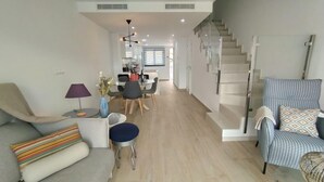 Una sala de estar moderna con un sofá, un comedor y una escalera.