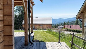 A wooden cabin with a deck, a metal gutter, and a view of mountains and a forest. - Chalet Amsel by Interhome (Sirnitz - Hochrindl)