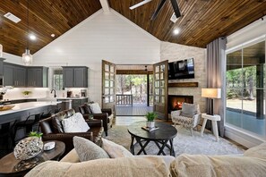 Un amplio salón con chimenea, asientos cómodos y vistas al exterior.
