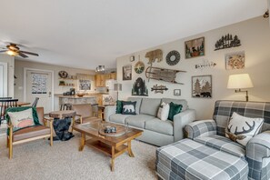Uma sala de estar acolhedora com lareira, área de jantar e cozinha.