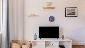 Ein modernes Wohnzimmer mit einem Flachbildfernseher auf einer weißen Unterhaltungsanlage, einer Uhr und zwei Regalen mit Dekoration.
