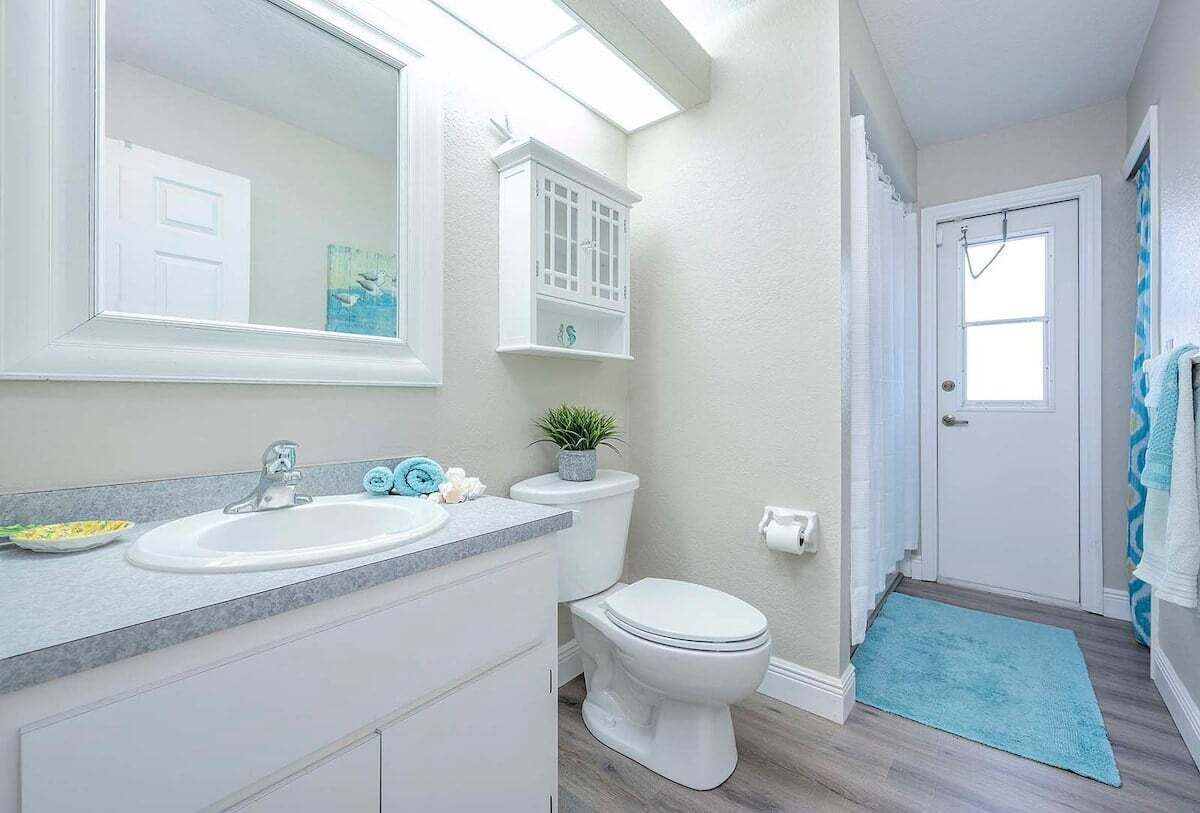 Une salle de bain avec un lavabo blanc, des toilettes et un meuble au-dessus des toilettes.