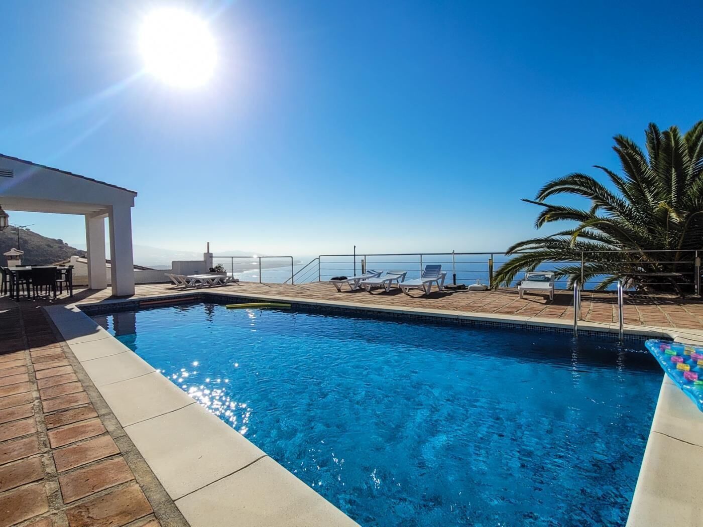 Ein Pool mit Blick aufs Meer, Liegestühle und eine überdachte Lounge-Ecke.