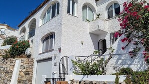 A white stucco building with arched windows, a stone wall, and a metal staircase. - Luxury villa with heated pool and sea views. (Salobreña)