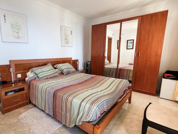 A bedroom with a bed, nightstands, a wardrobe, and a mirror.