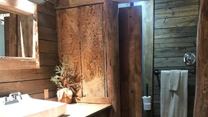 Un baño rústico con tocador de madera, un lavabo, un espejo y un perchero para toallas.