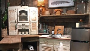 Una cocina rústica con armarios de madera, horno empotrado, un lavabo y un refrigerador.