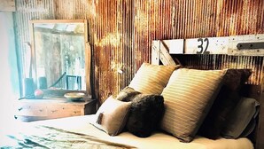 Un dormitorio con una cama, almohadas, una colcha y un cabecero de madera con el número 32.