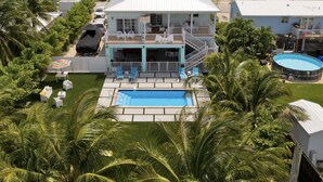 Ein zweistöckiges Haus mit Balkon, Swimmingpool und umzäunter Garten.