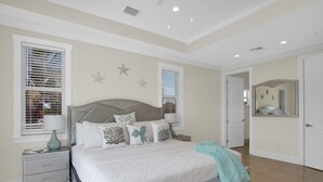 Ein Schlafzimmer mit einem Bett, Nachttischen, einem Spiegel und einer Tür.
